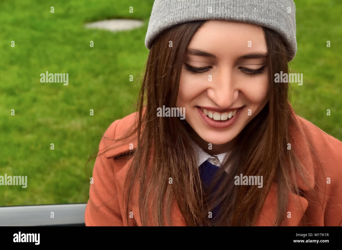 Ritratto di una bella ragazza europea sulla strada. Vestito di un cappello, marrone capelli. Sorrisi, guarda verso il basso Foto Stock