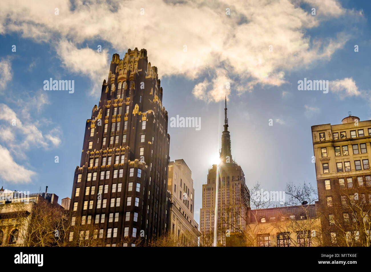 New York City, New York, USA, gennaio 2018, l'American Radiator Building e il sole dietro l'Empire state Building di Manhattan Foto Stock