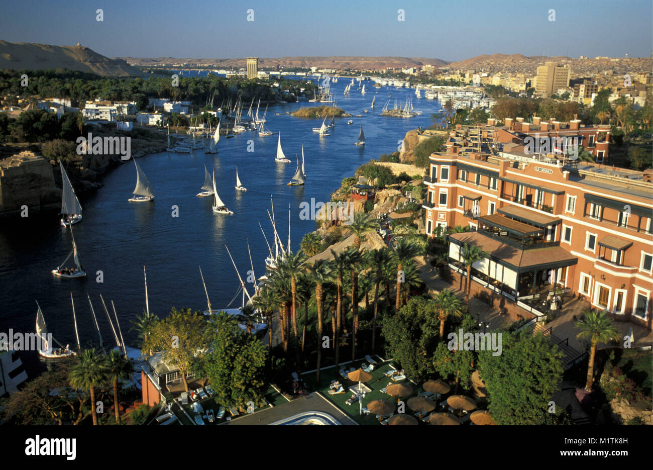 L'Egitto. Aswan. Fiume Nilo. Feluche (tradizionale le navi a vela). Nella parte anteriore: la Old Cataract Hotel, famoso e storico hotel. Foto Stock