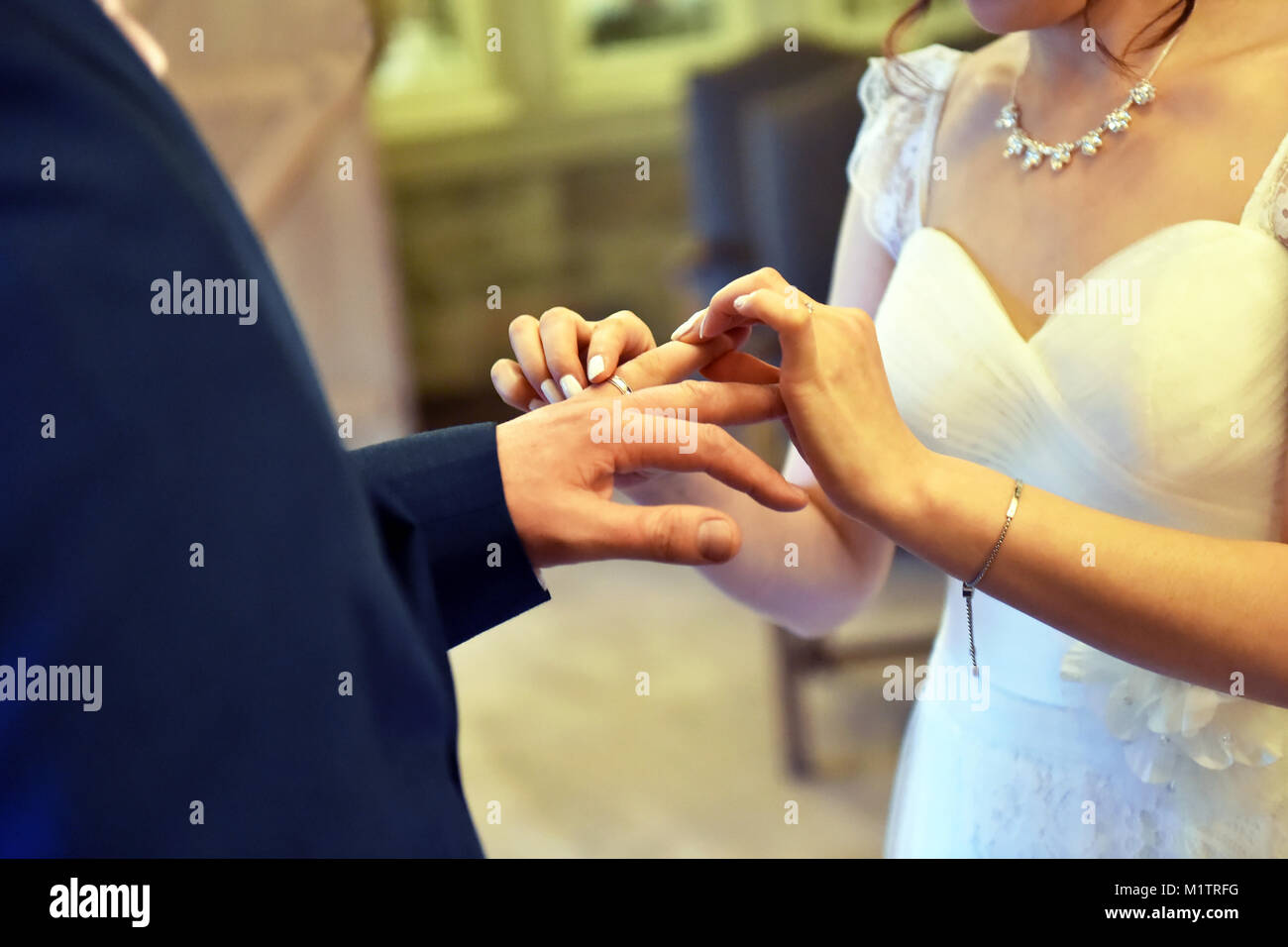 Wedding scambio di coppia anelli sul loro giorno delle nozze, close up posizionando l'anello sul dito. Foto Stock