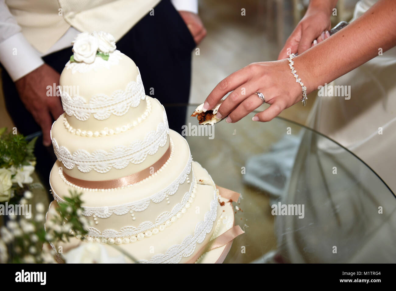 Coppie in viaggio di nozze tagliato in loro torta di nozze di prendere una piccola fetta, solo le mani in mostra.UK Foto Stock