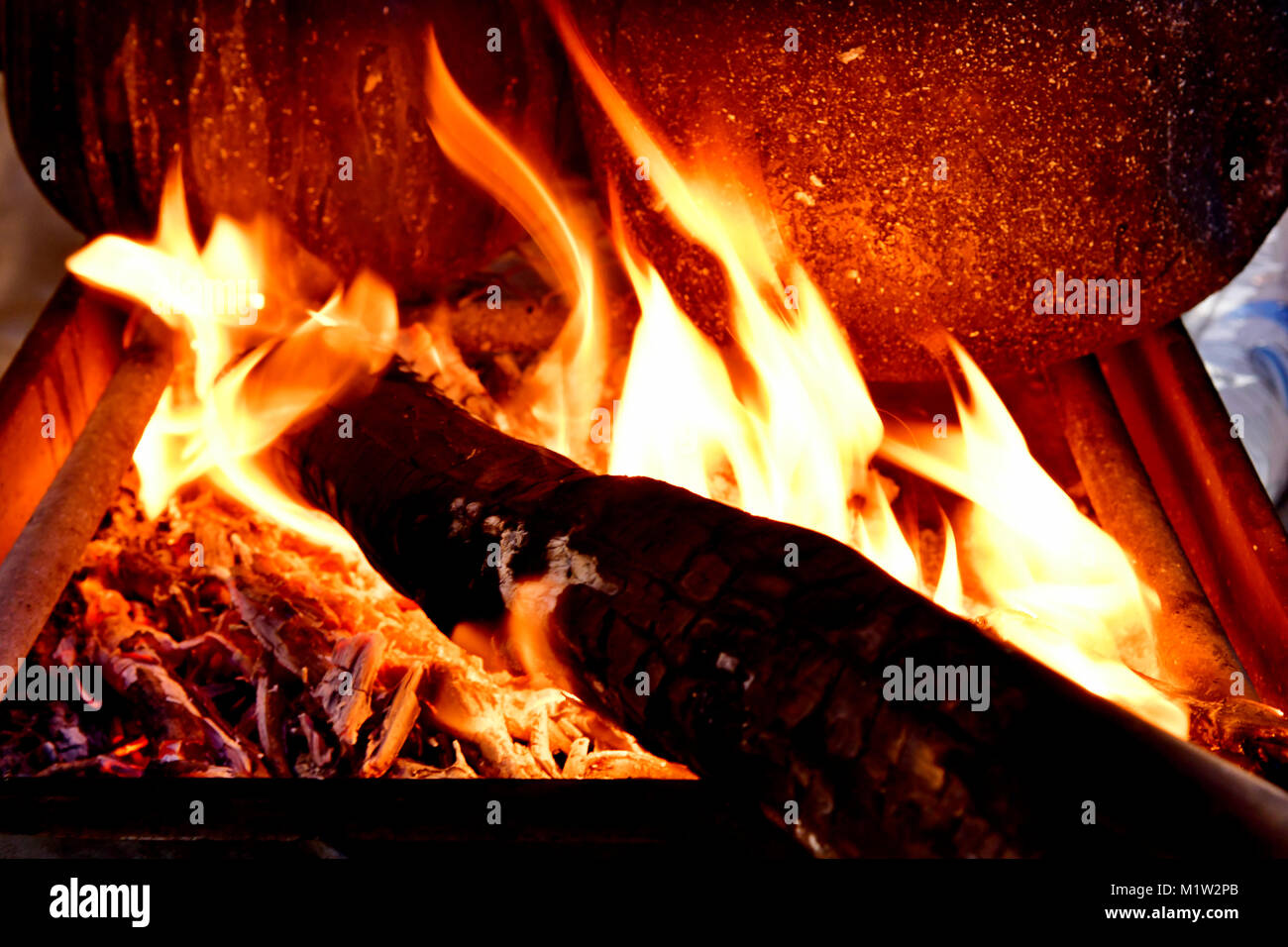Fuoco su legno con fiamme a caldo per preparare caffè arabo su speciali caffè tradizionale pots in strada Foto Stock