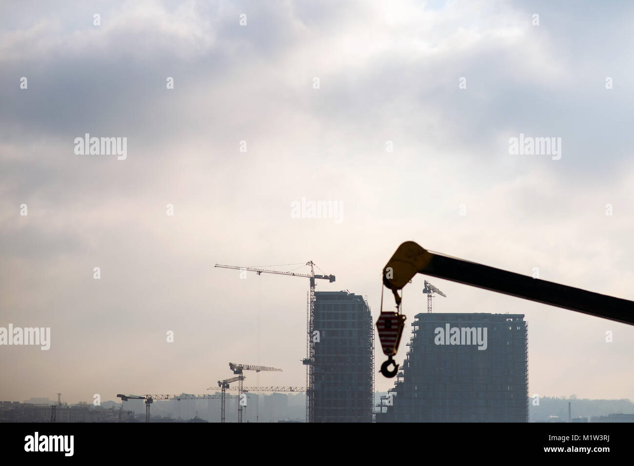 La costruzione di un edificio moderno con macchine e gru lavorando su un sito in costruzione Foto Stock