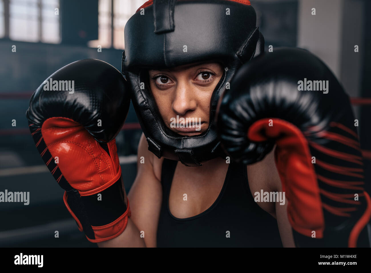 Close up di un boxer femmina nel suo ingranaggio di inscatolamento. Donna boxer in un boxing studio indossando la protezione della testa e i guantoni. Foto Stock