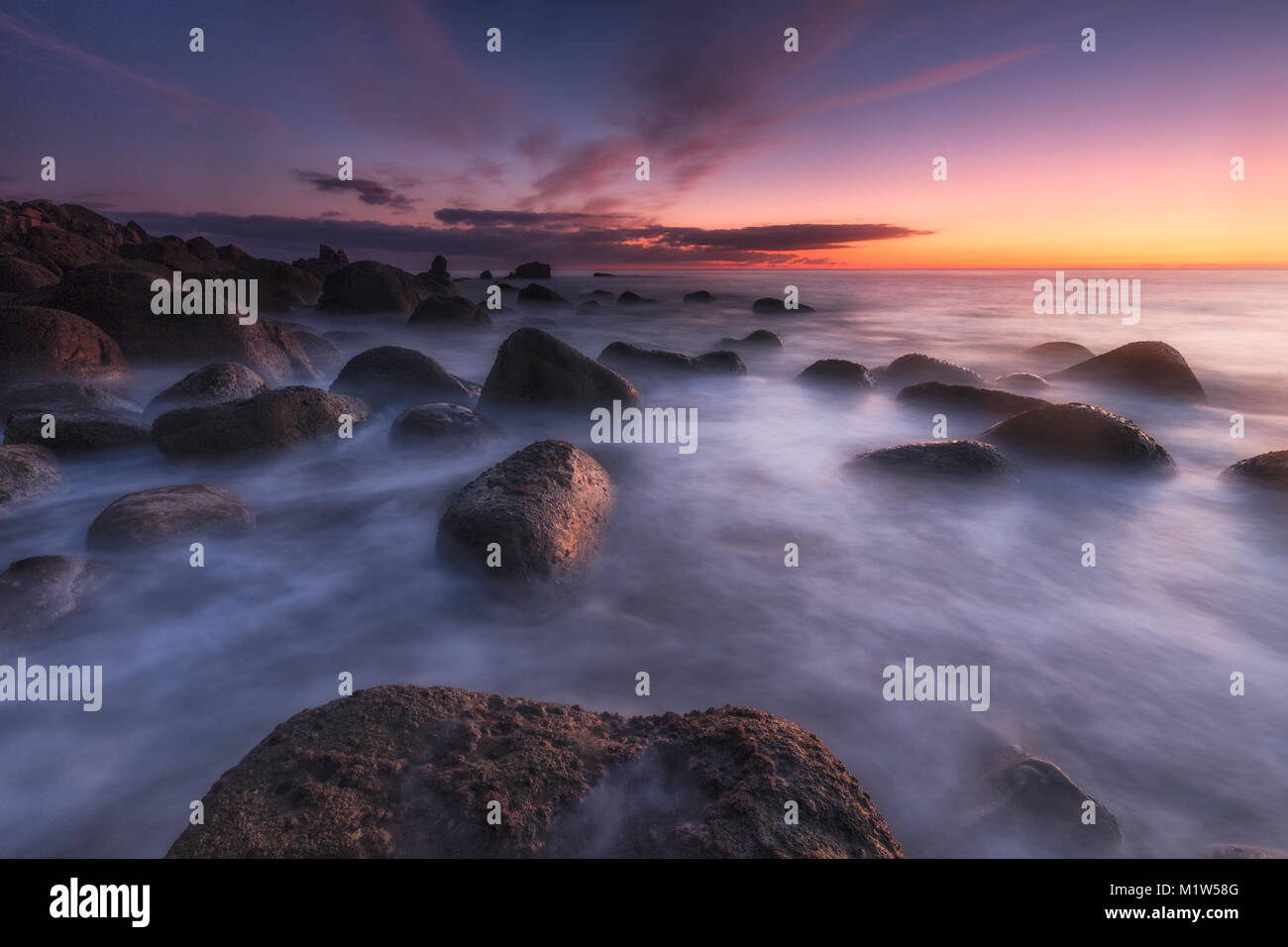 Tramonto su un mare calmo a Arribolas beach a Bermeo, Bizkaia Foto Stock