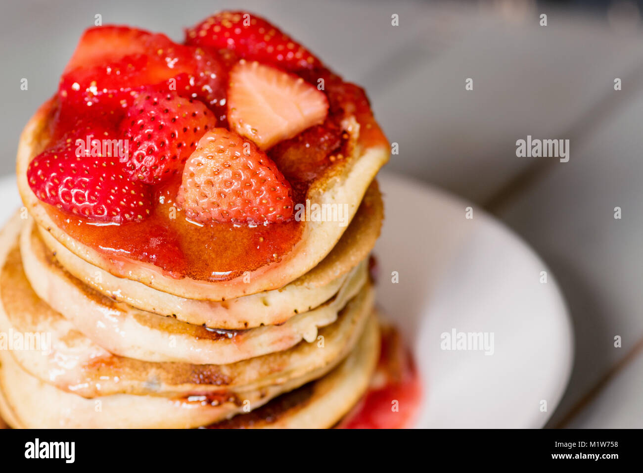 Deliziose frittelle di fragole al buio su un sfondo moody, una straordinaria prima colazione con colori vibranti, piastra bianca Foto Stock