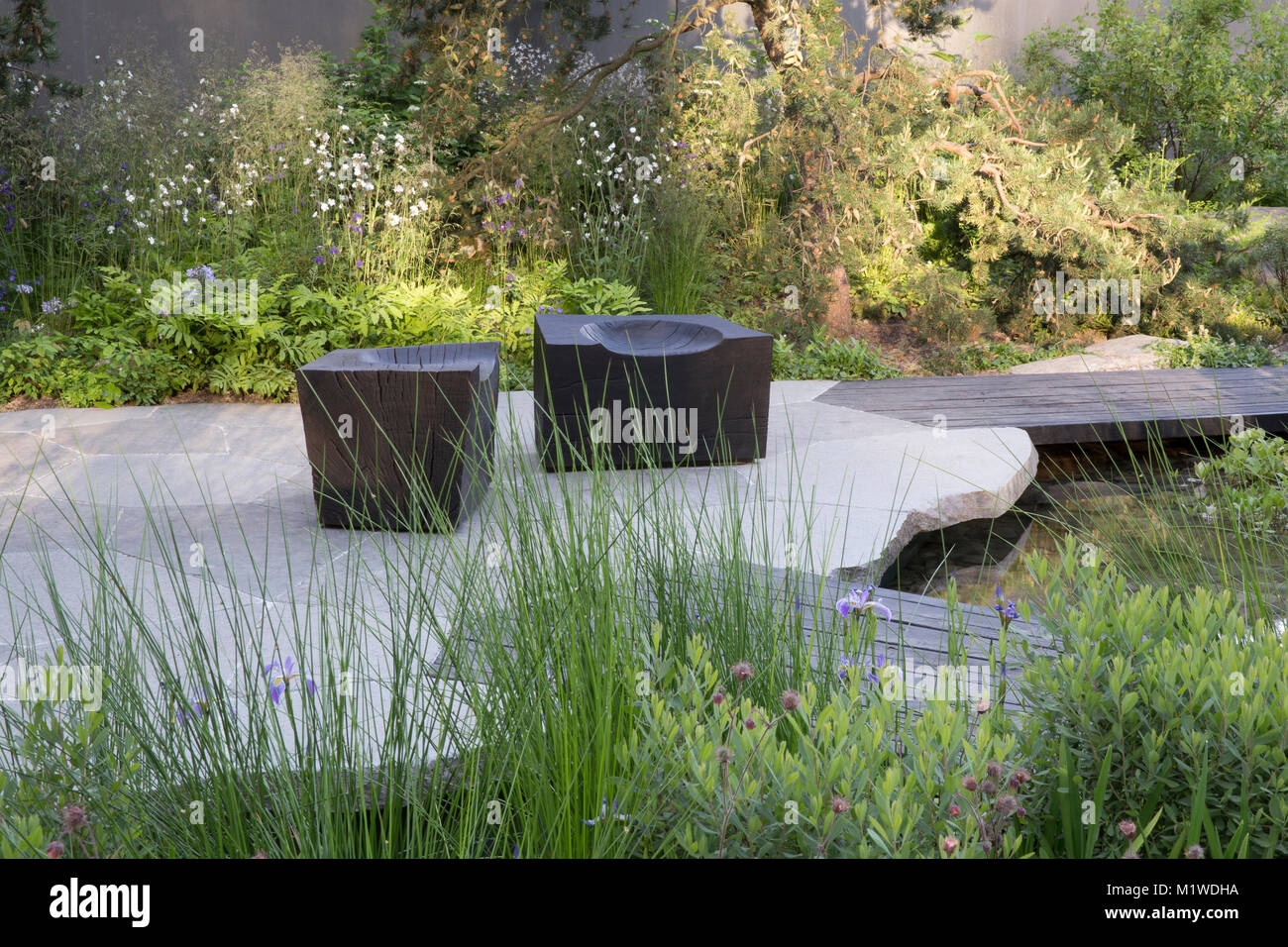 Banca del Canada giardino, il Chelsea Flower Show 2018 scuro passerella in legno sulla piscina, carbonizzati cubo di legno sede Foto Stock