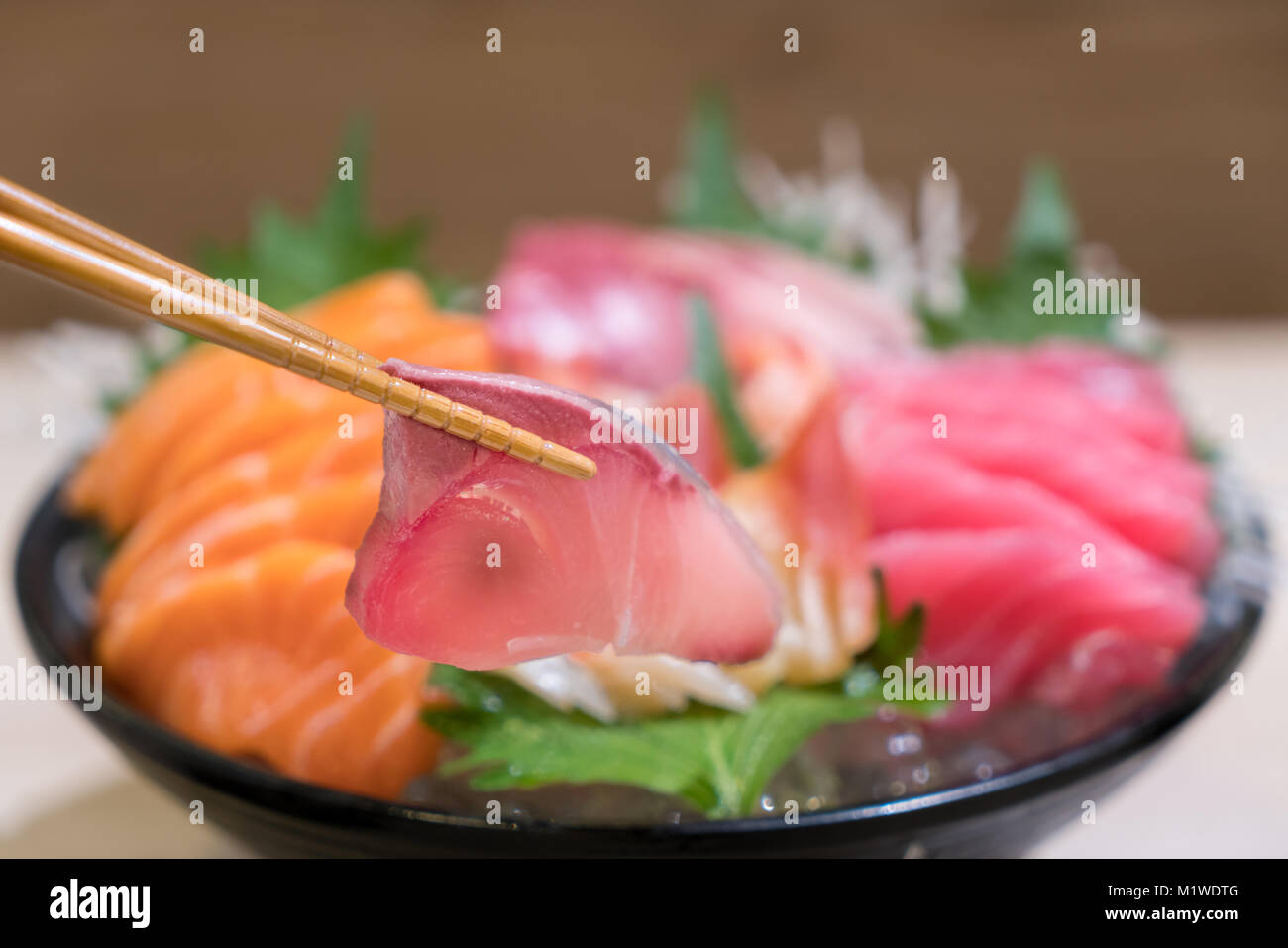 Bacchette con Hamachi sashimi con affettato misto sashimi di pesce su ghiaccio in nero ciotola. Sashimi di tonno salmone Hamachi di gamberi e Surf calma impostare, pesce crudo, ja Foto Stock