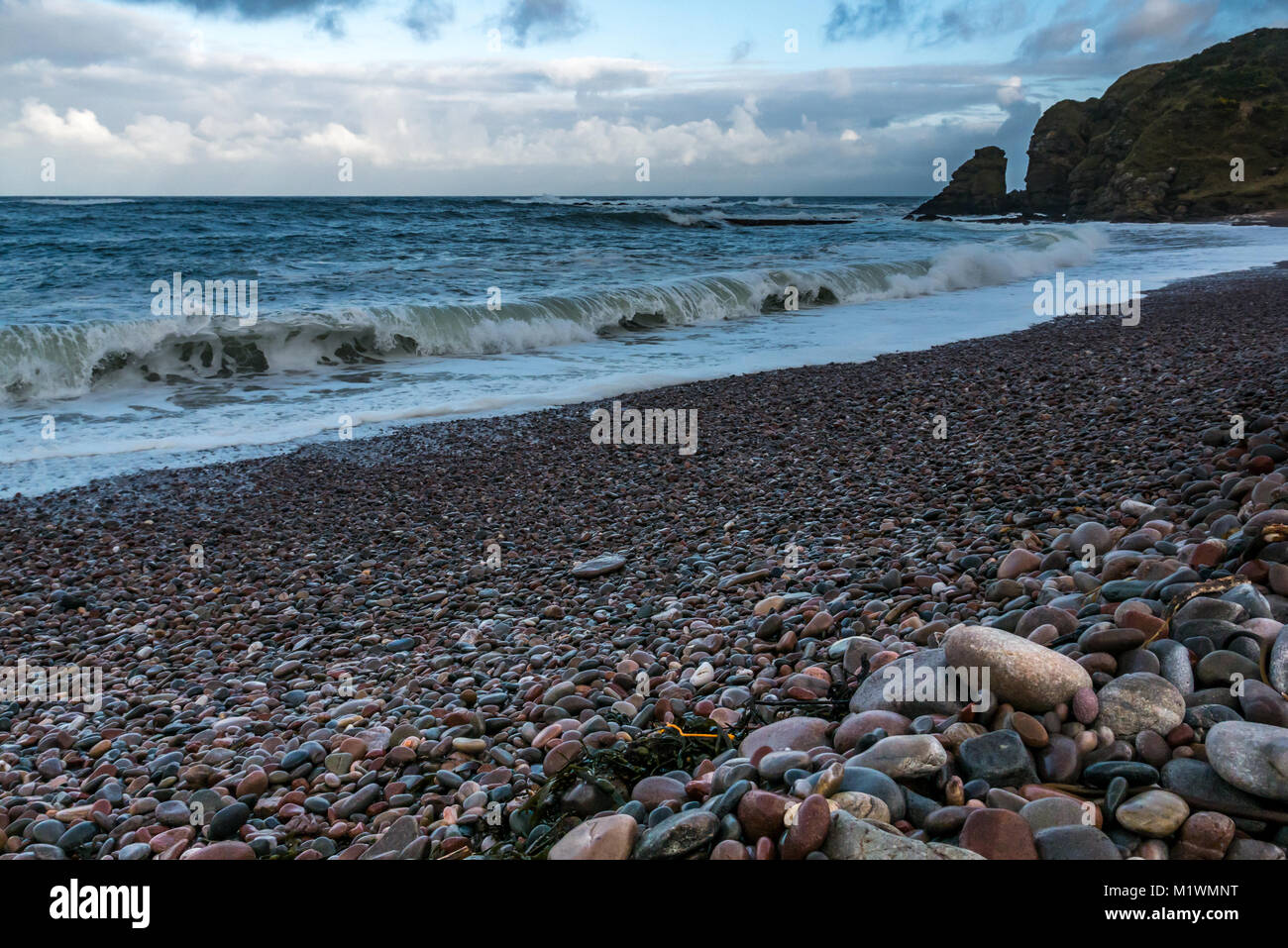 Aberdeenshire, Scotland, Regno Unito. Il forte vento crea un sovraccarico nel Mare del Nord lungo la costa nord-est della Scozia, con grandi onde che si infrangono sulla riva di una spiaggia di ciottoli Foto Stock