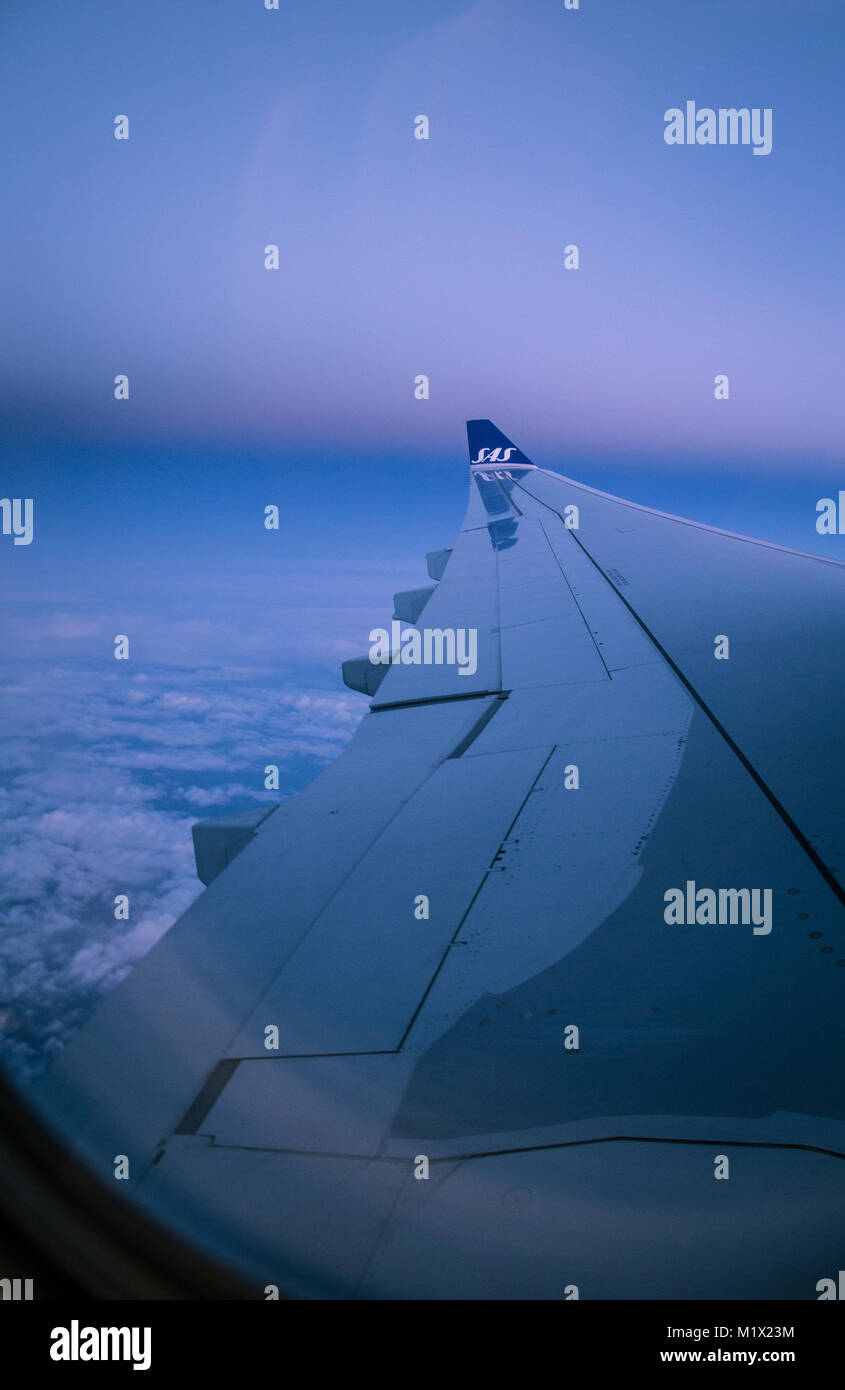 Vista di un'ala di aeroplano su una Scandinavian Airlines (SAS) volo a sunrise contro un cielo nuvoloso, in volo da Los Angeles a Stoccolma. Foto Stock