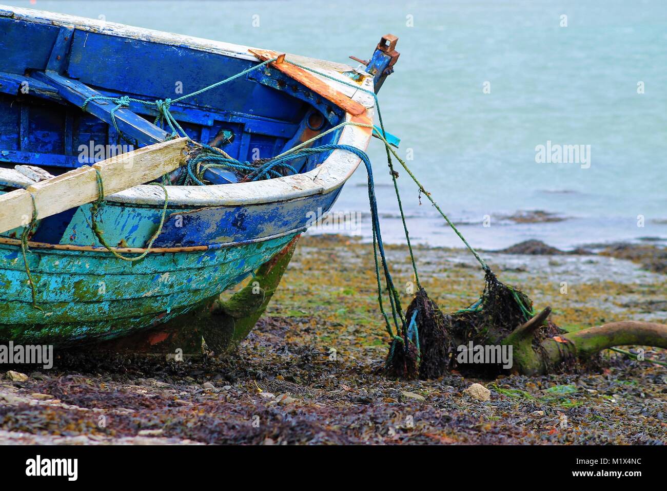 Nave naufragata la barca di legno abbandonato e legato su di una spiaggia di ciottoli Foto Stock