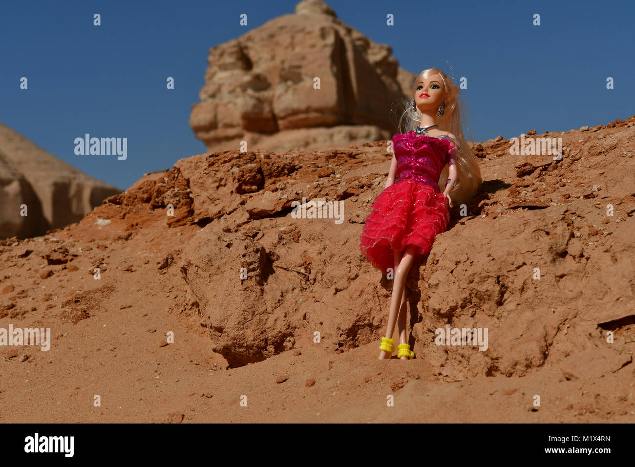 Barbie ragazze vestito di rosso e blu sono in posa per la modellazione di foto nel deserto rocce sulla posizione Foto Stock