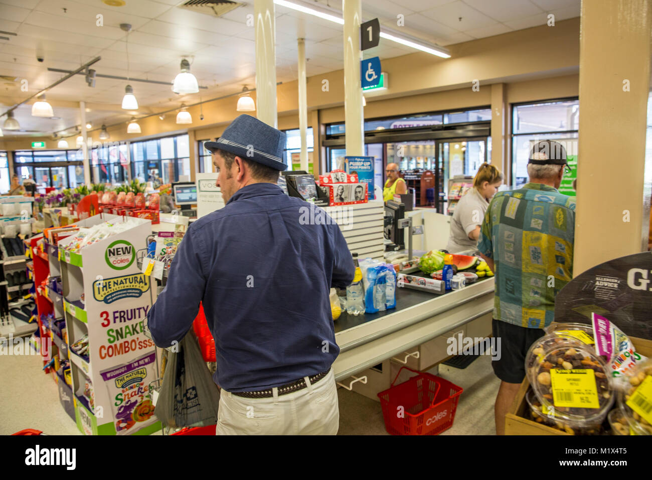 Uomini alla cassa che acquistano generi alimentari in un supermercato Coles nel Queensland, Australia Foto Stock