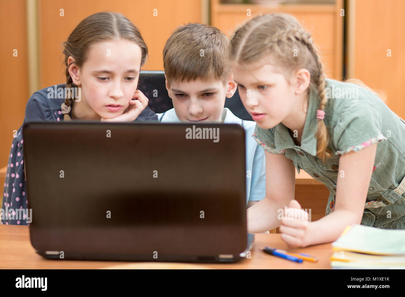 Felice la scuola dei bambini al computer portatile in aula Foto Stock