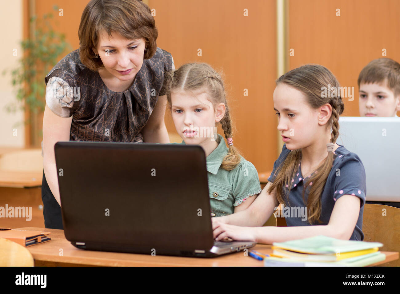 I bambini della Scuola e insegnante al computer portatile in aula Foto Stock