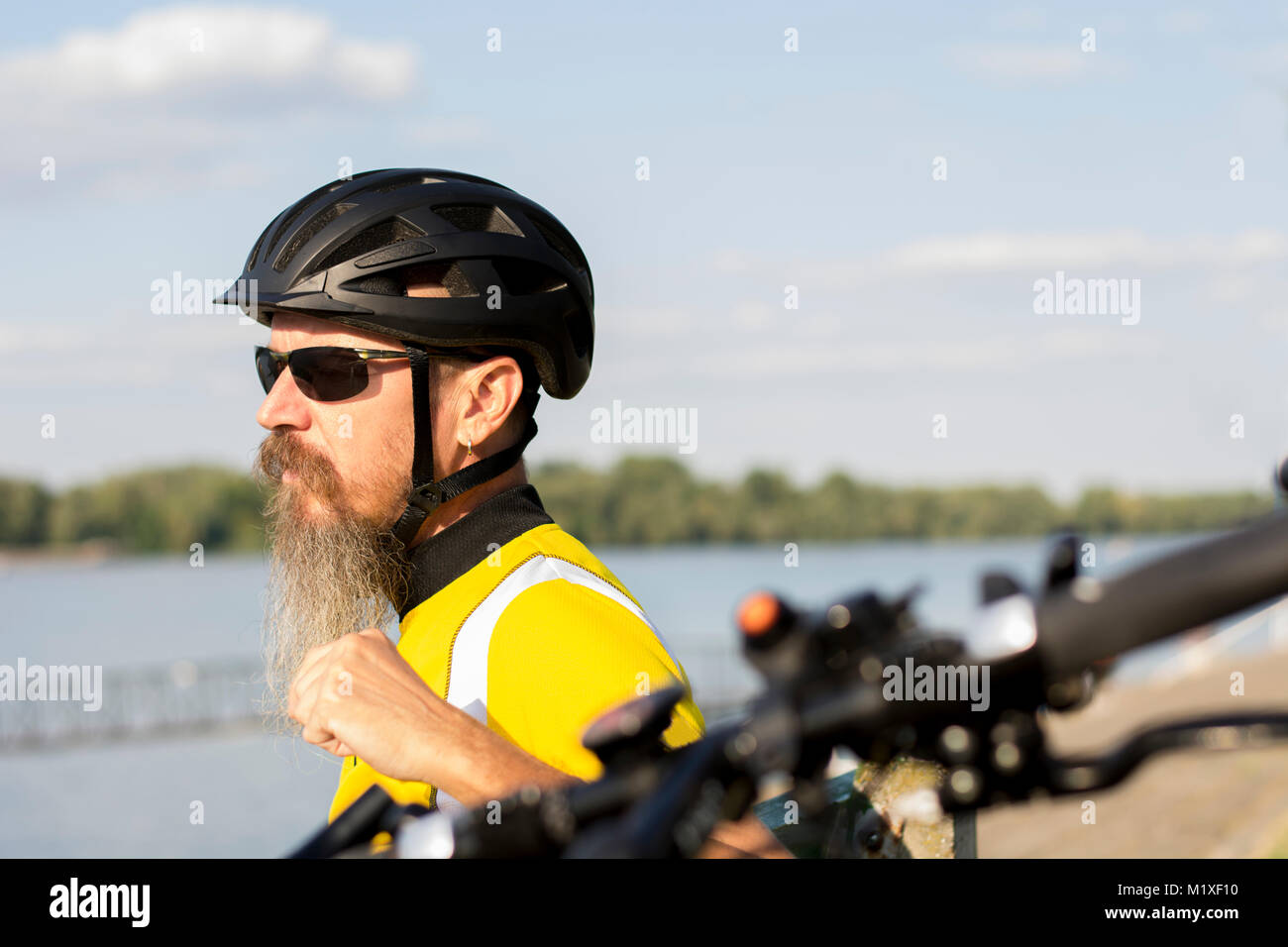 Ciclista maschio in appoggio e guardando il fiume Foto Stock