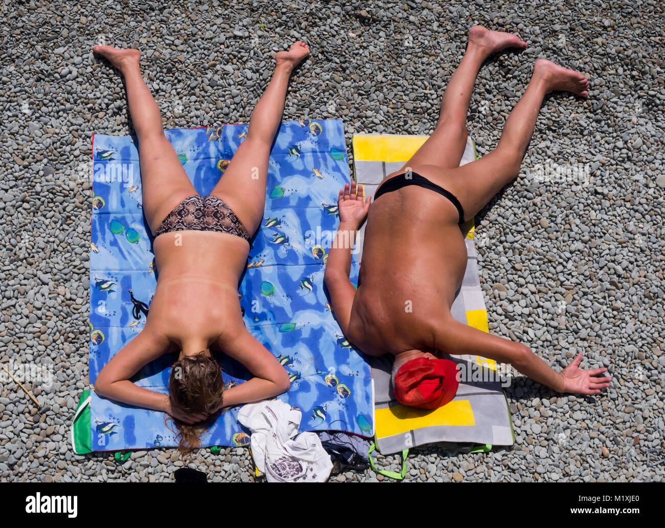 L uomo e la donna sono a prendere il sole sdraiati sulla spiaggia Foto Stock