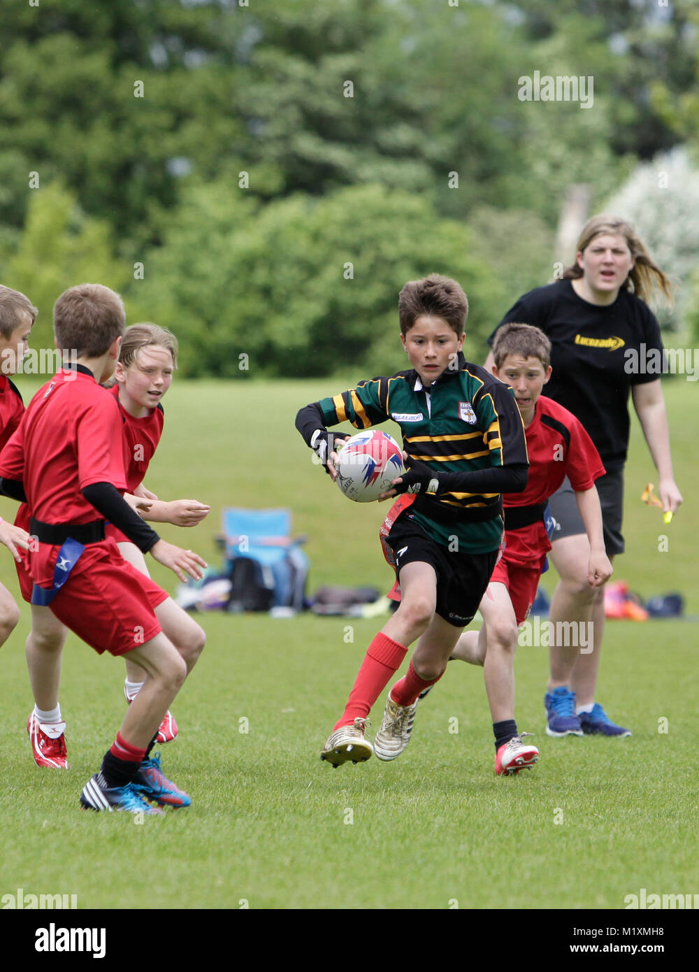 Ragazze e ragazzi giocando Tag Rugby nelle Midlands in un pomeriggio piovoso in primavera. Foto Stock