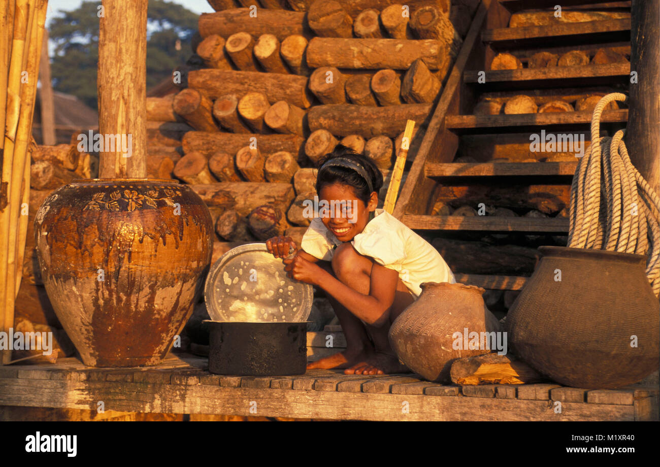 Myanmar (Birmania). Mandalay. Ragazza facendo il lavaggio delle stoviglie. Fuelwood in background, la legna da ardere. Foto Stock