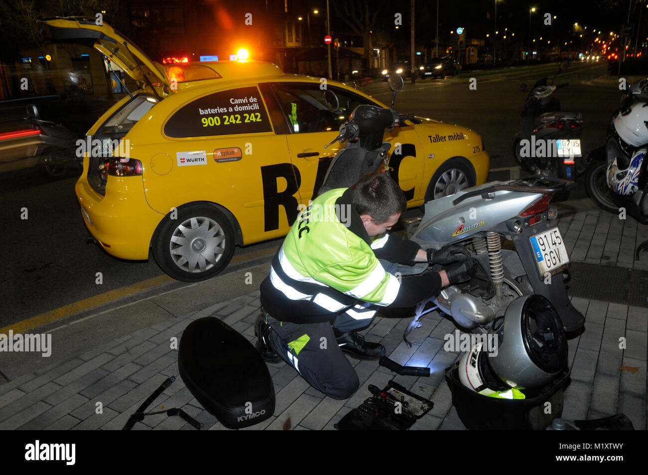 Uno specialista è la riparazione di uno scooter di notte sulla città di Barcellona Foto Stock
