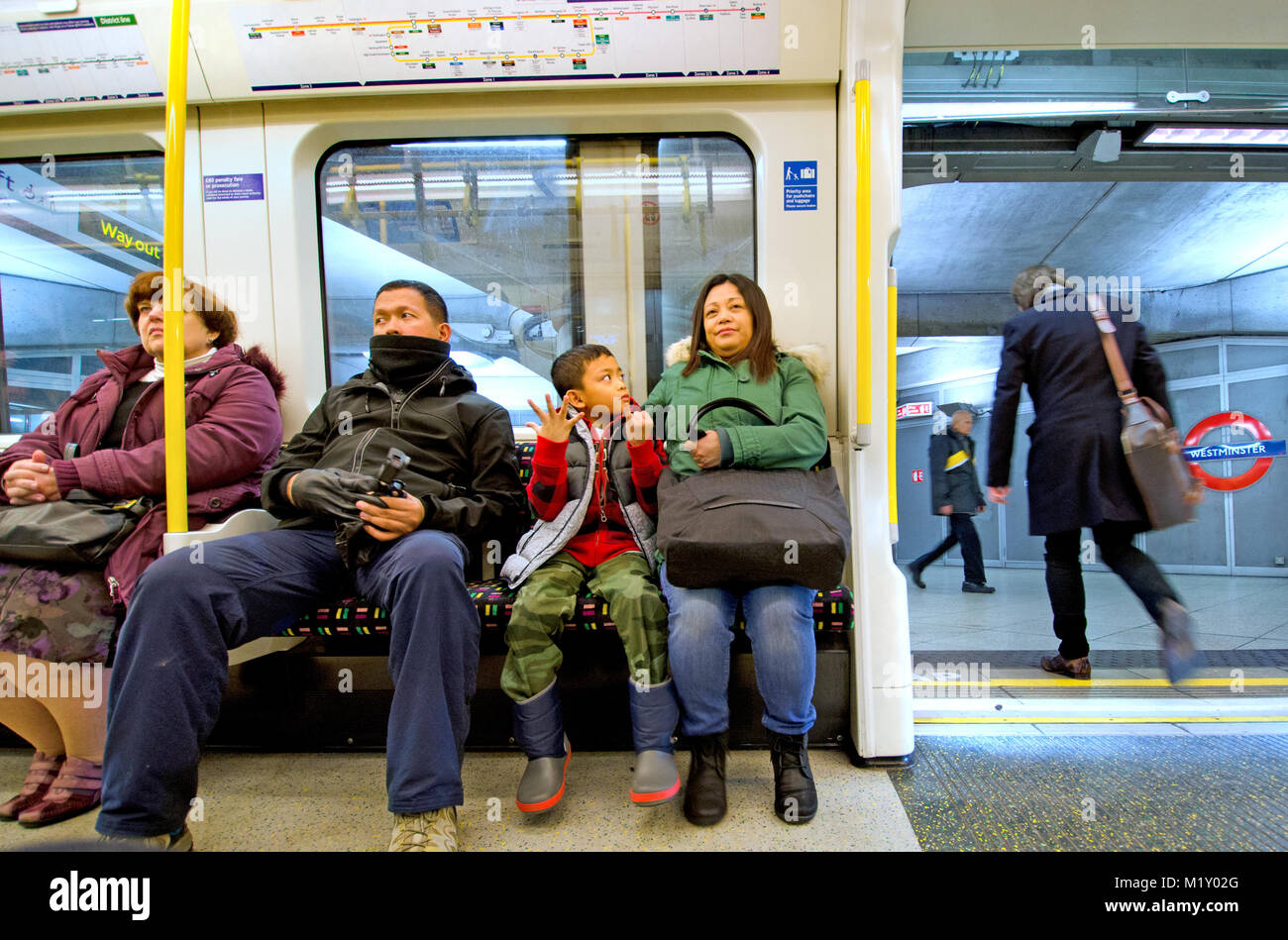 Londra, Inghilterra, Regno Unito. Famiglia asiatica su un treno di tubo Foto Stock