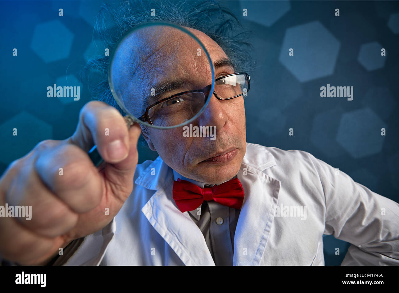 Scienziato in camice bianco facendo analizzare guardando attraverso una lente di ingrandimento Foto Stock