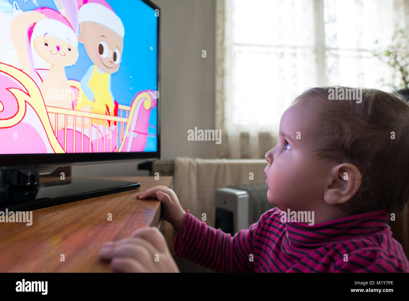 Bambina guarda la TV. Di fronte alla TV. Foto Stock