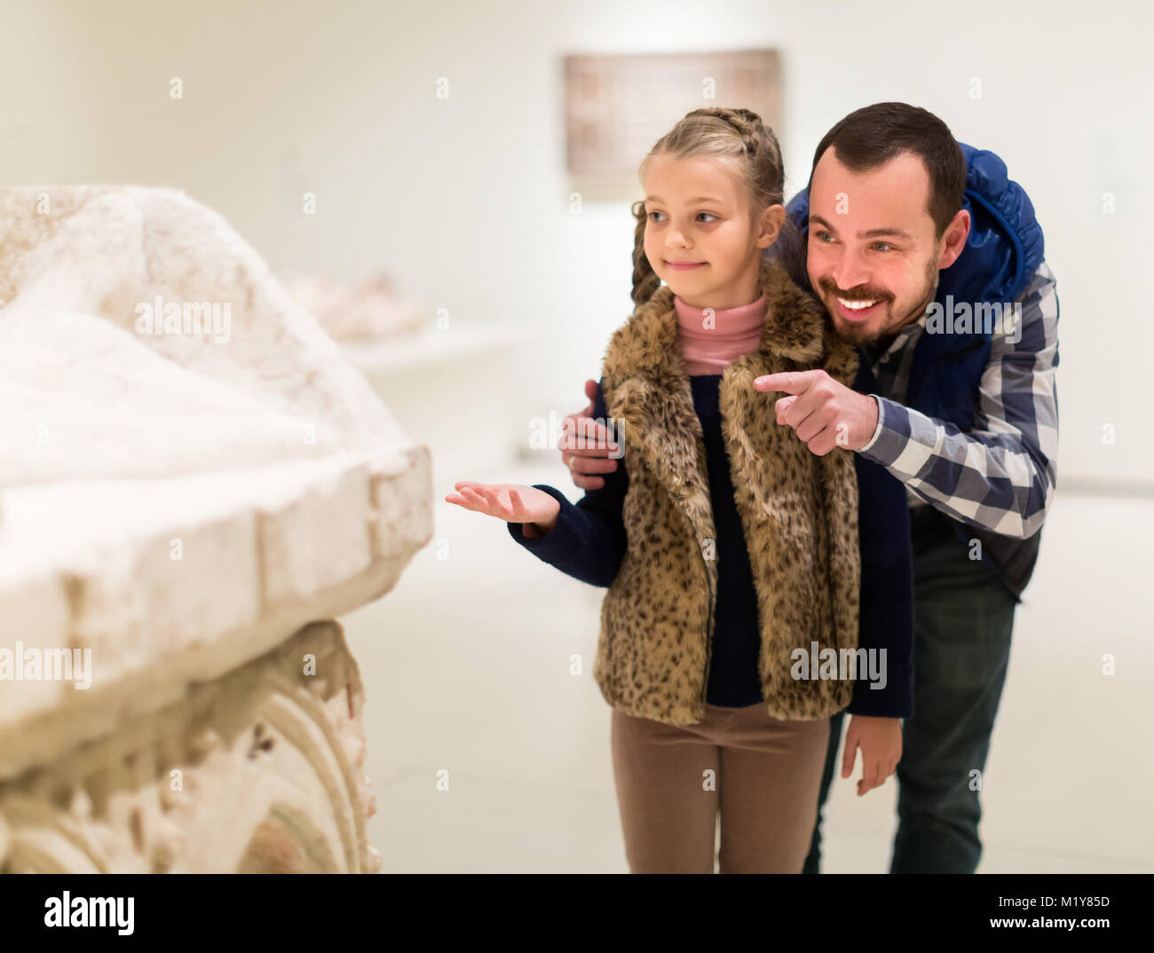 Maschio positivo e piccola figlia cercando di antichi bassorilievi in museo Foto Stock
