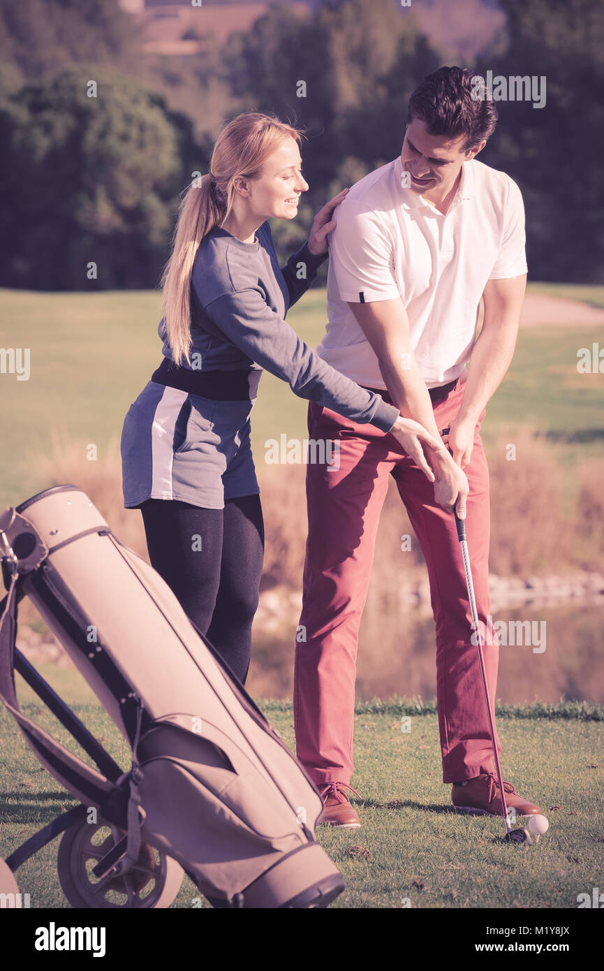 Positivo donna giovane golfista uomo di formazione per giocare a golf e colpire la sfera correttamente Foto Stock