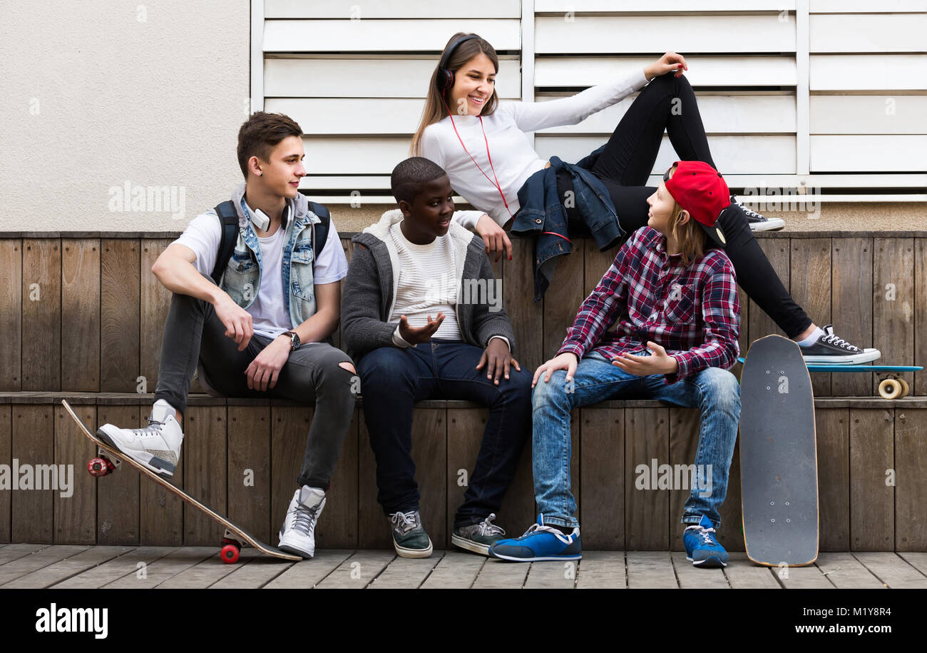 Felice la ragazza spagnola e tre ragazzi appendere fuori all'aperto e discutere di un argomento Foto Stock