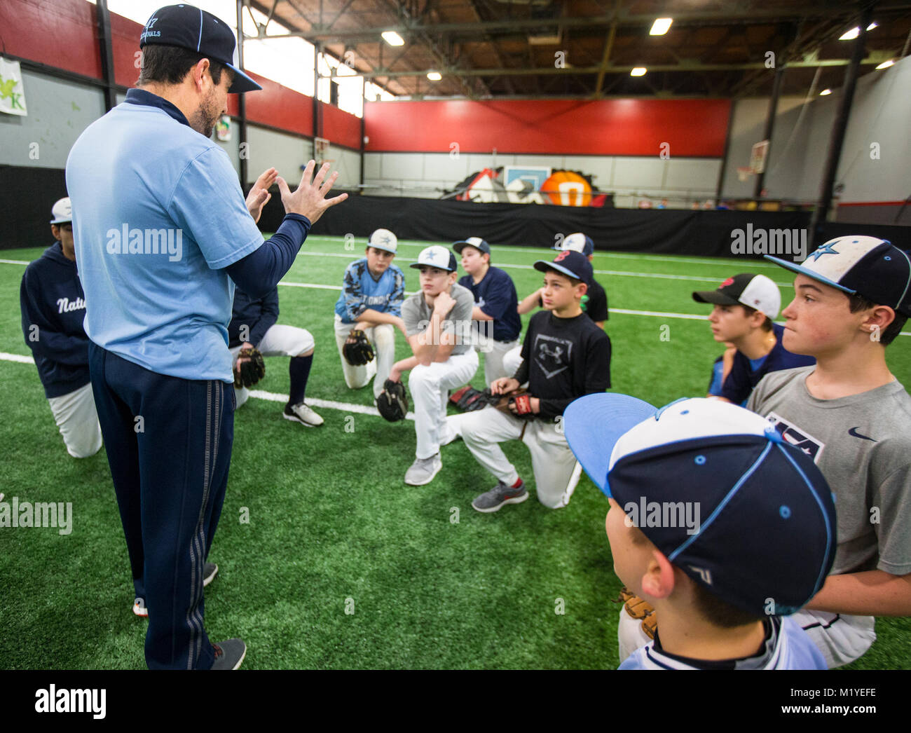 Il baseball coach parlando con i giocatori di allenamento indoor facility in New Jersey Foto Stock