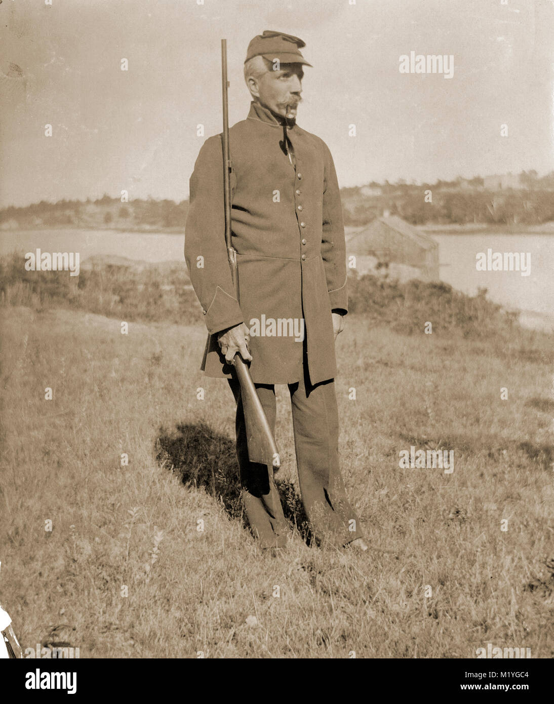 Antique circa 1905 fotografia, anziano gentiluomo con fucile in uniforme militare. La posizione è in o vicino a Riggsville (ora Robinhood), Maine in Sagadahoc County, Stati Uniti d'America. Foto Stock