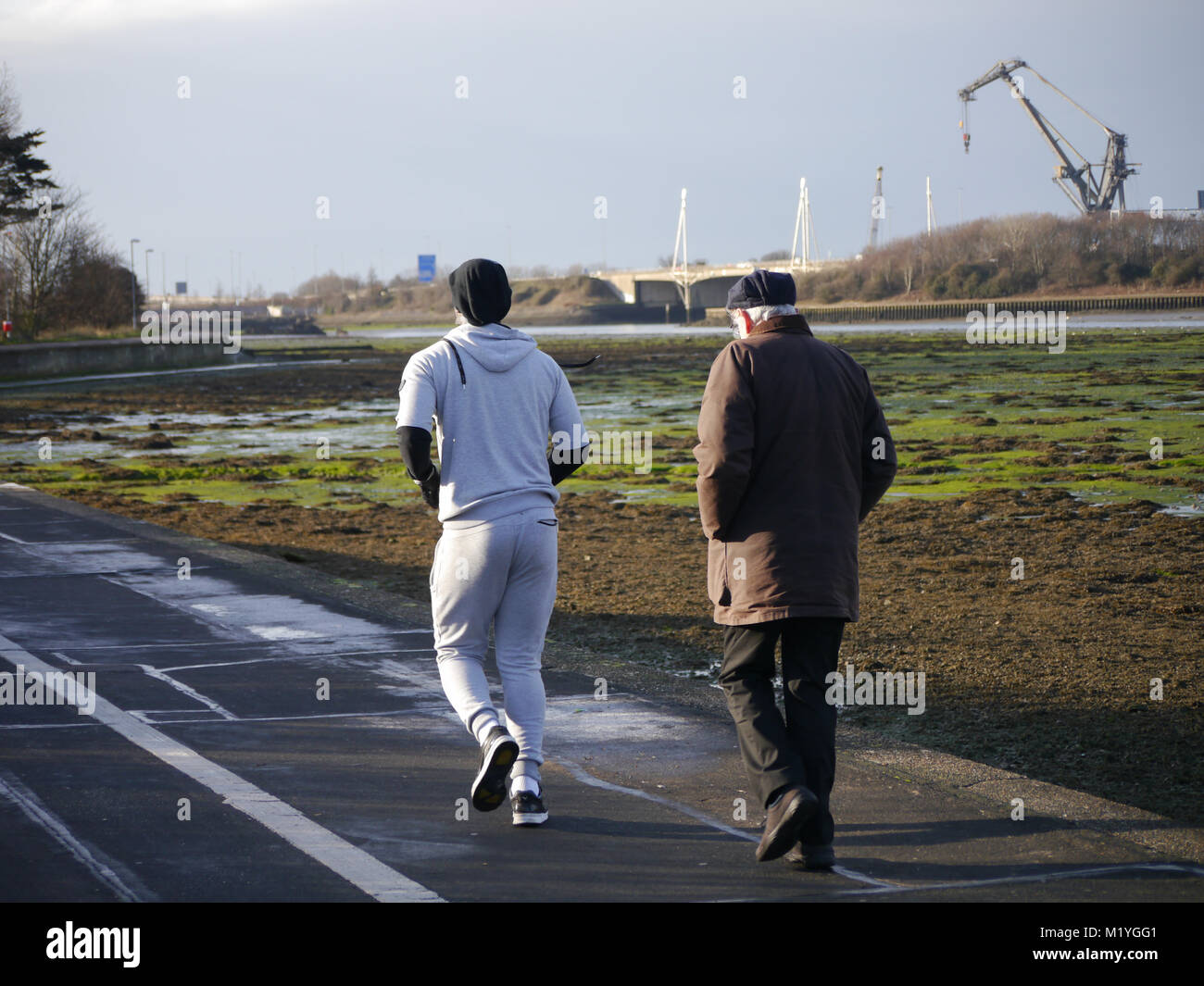 Un giovane uomo oltrepassa un maschio senior mentre il jogging Foto Stock