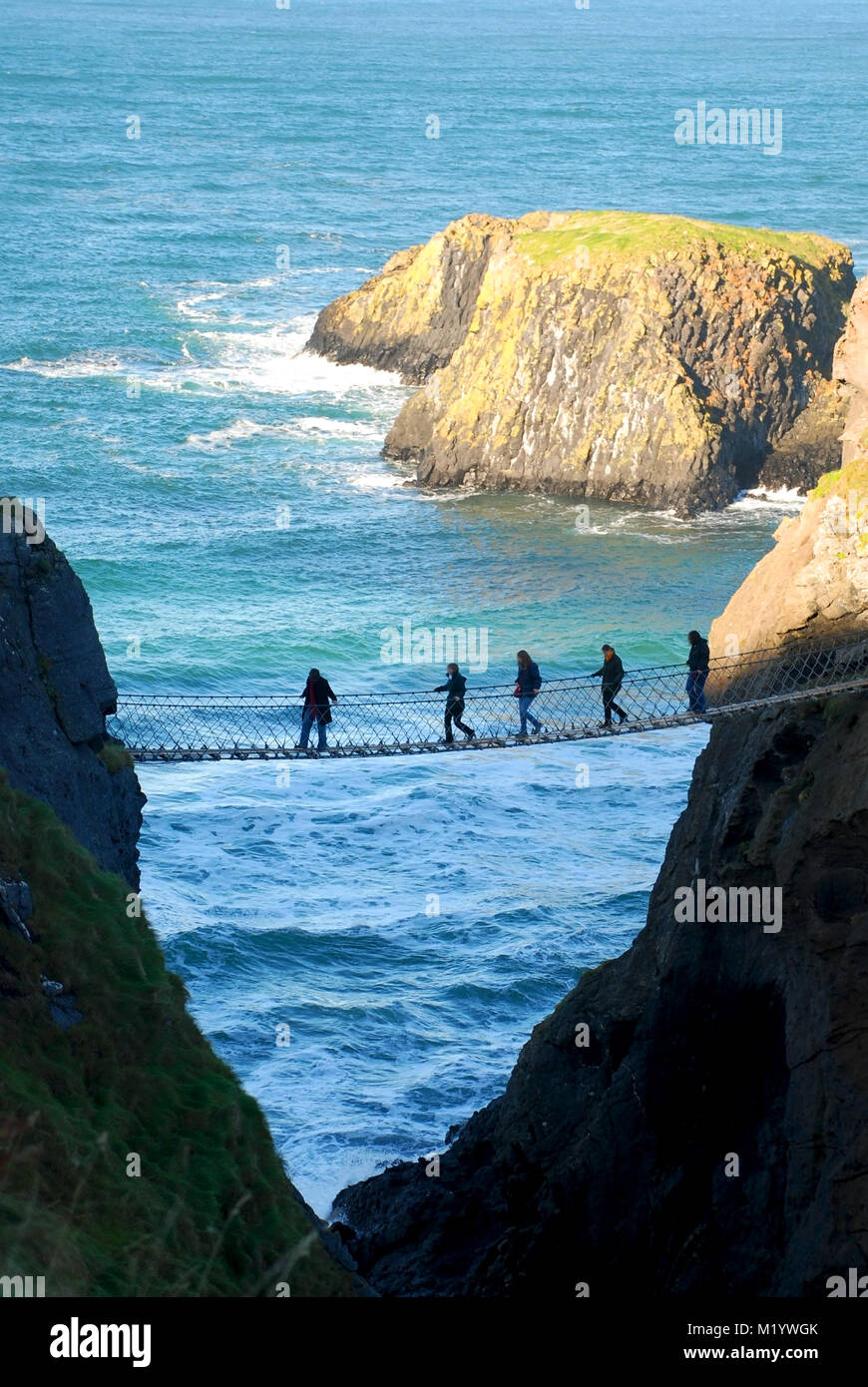 Amici attraversando il ponte di corde in Carrick-a-Rede, County Antrim, Irlanda del Nord, Regno Unito Foto Stock
