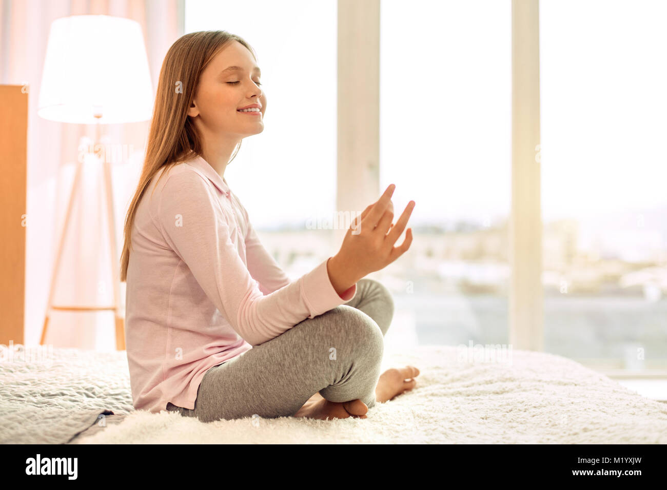 Piacevole ragazza adolescente a praticare yoga sul letto Foto Stock