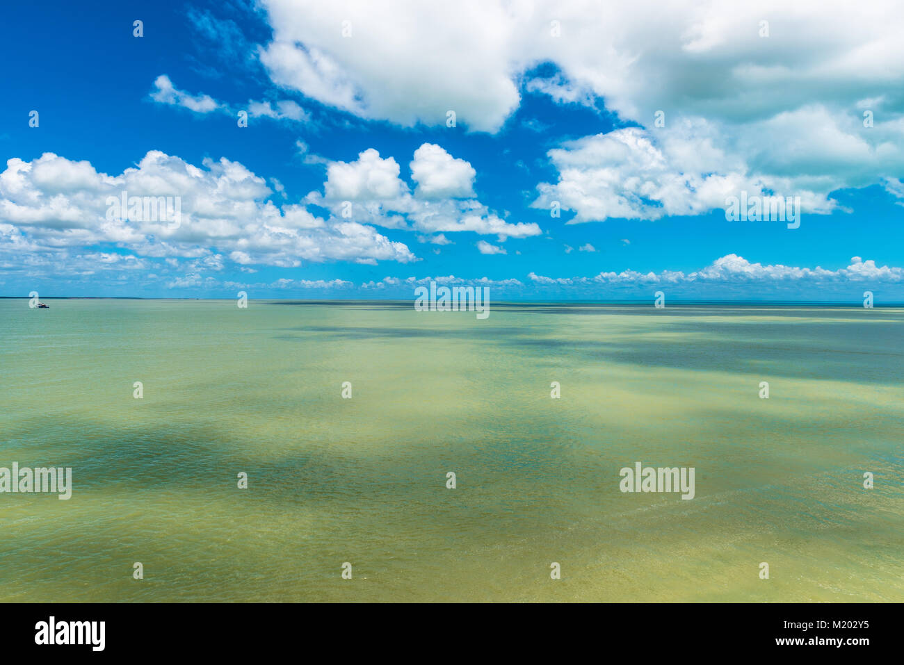Piccola barca a sinistra dall'orizzonte fornisce la prospettiva contro il vasto mare e cielo Foto Stock