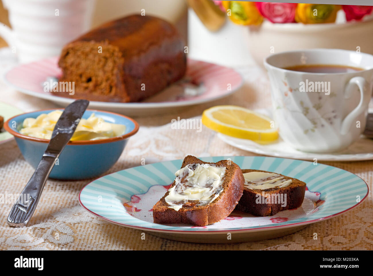 Impostazione tabella con malto a fette di pane con burro e il tè nero con il limone Foto Stock