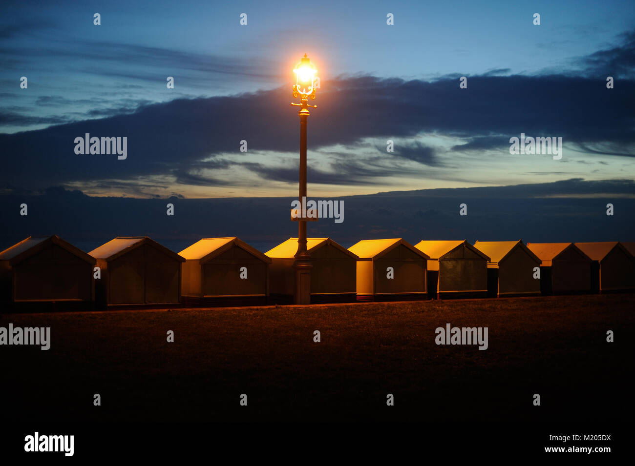 Spiaggia capanne su prati di Hove illuminato dalla luce artificiale alla fine della giornata Foto Stock