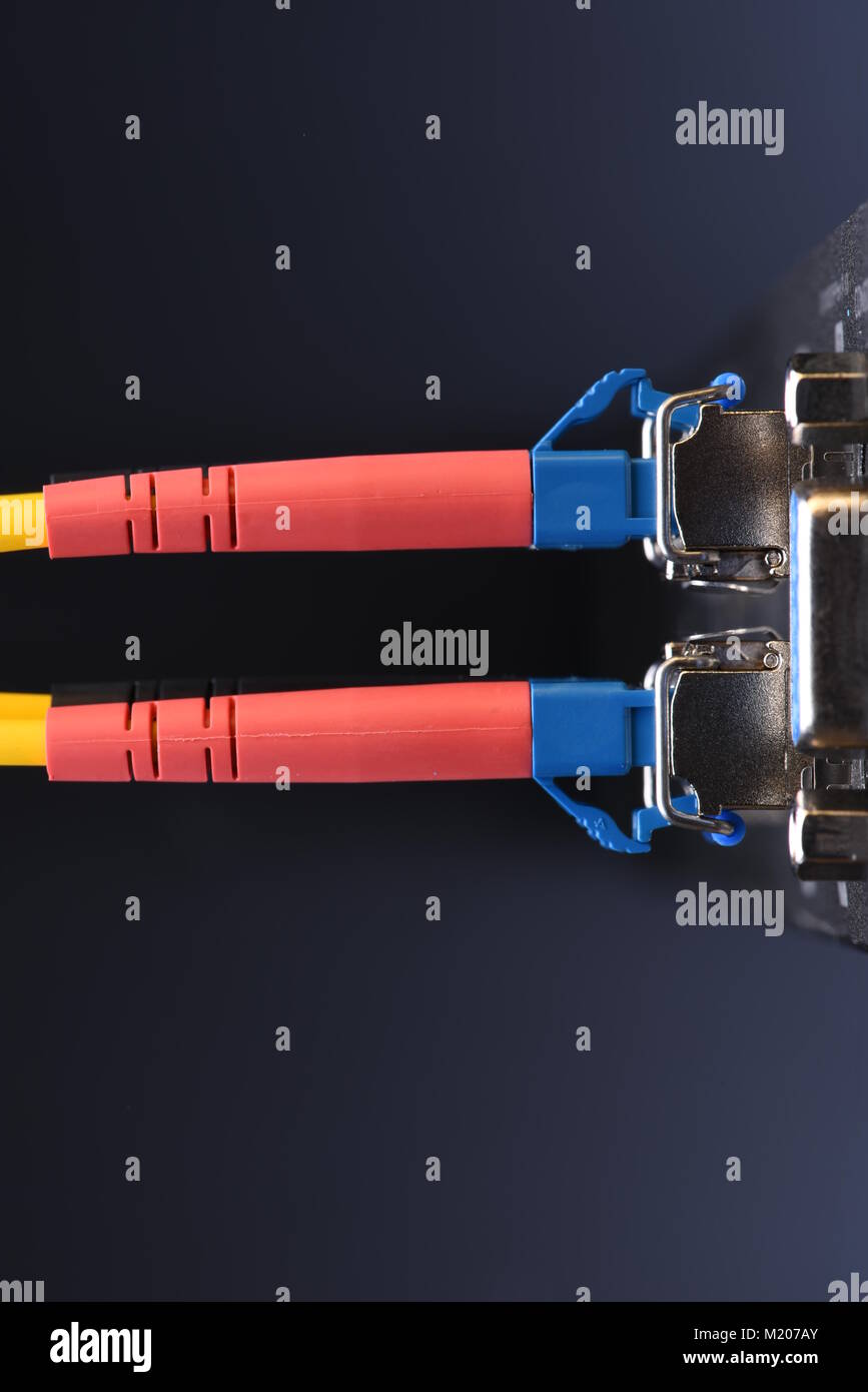 Dispositivi di rete tecnologia, cavo in fibra ottica e interruttore, close-up su sfondo nero Foto Stock