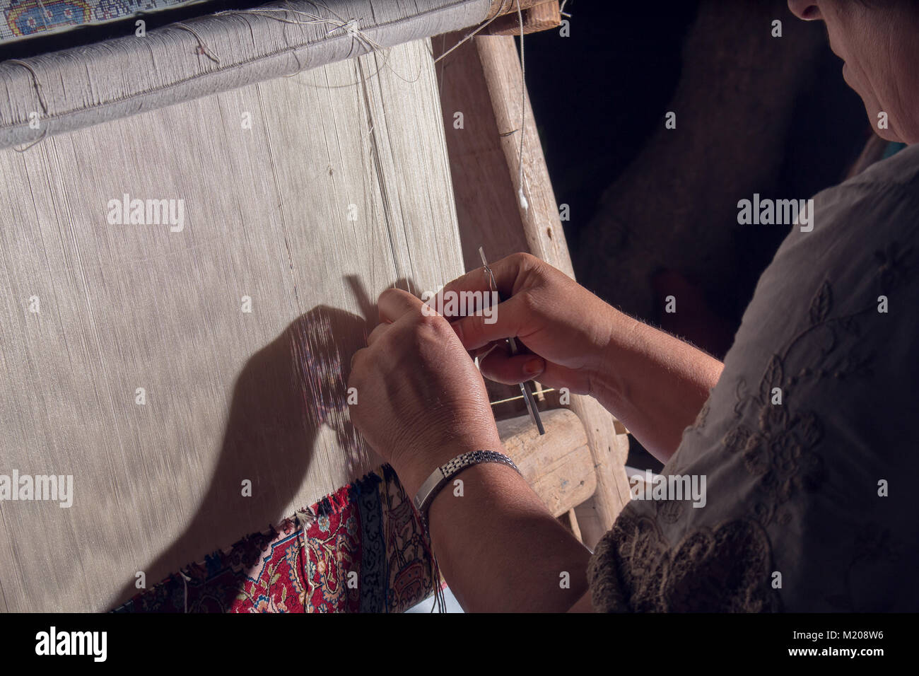 Invertire le donne illuminate tappeto di tessitura sul telaio con le mani Foto Stock