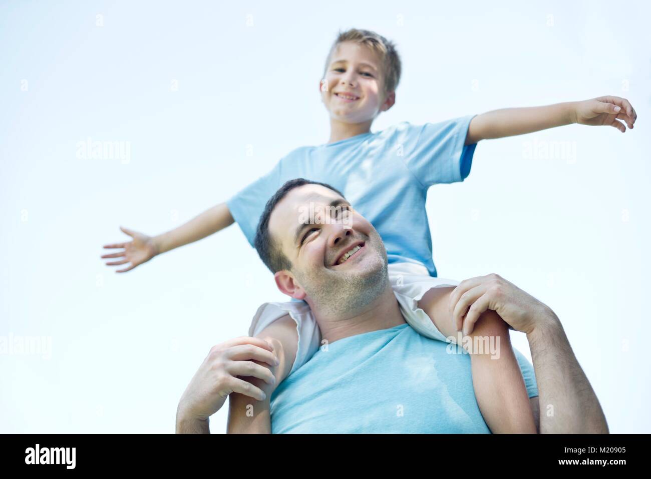 Padre figlio che porta sulle spalle, ragazzo con le braccia fuori. Foto Stock