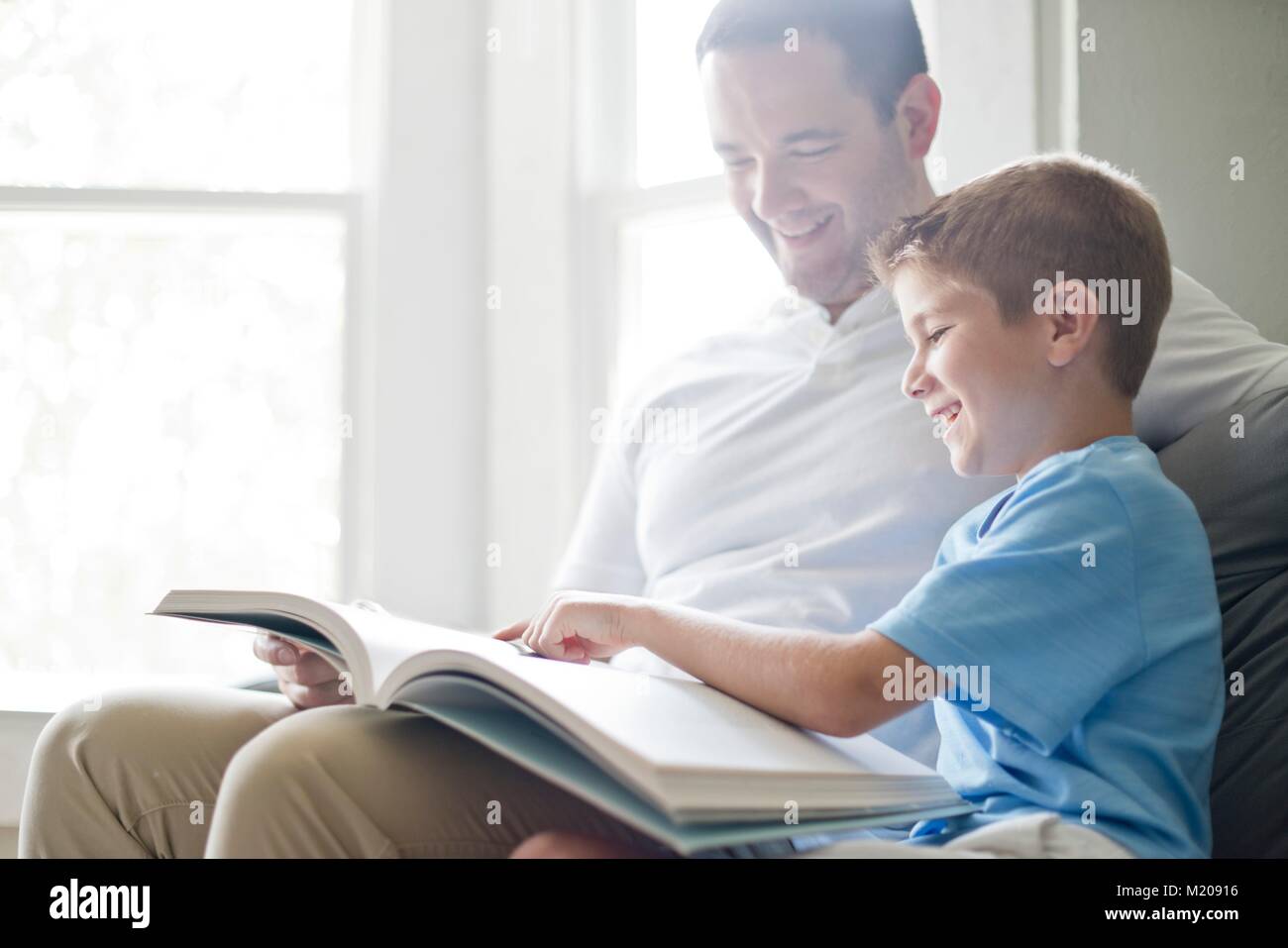 Ragazzo lettura prenota con suo padre. Foto Stock
