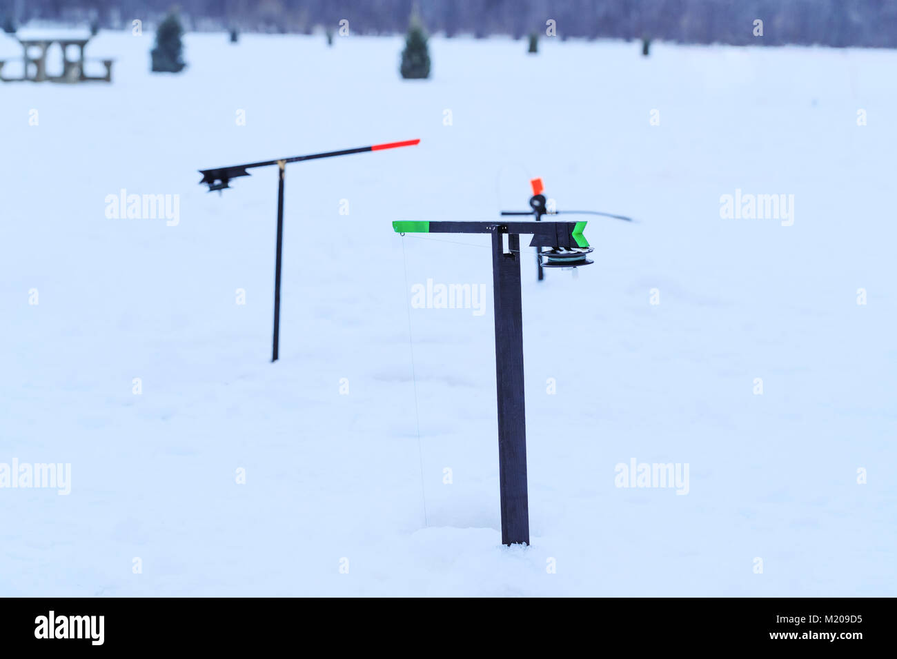 La pesca affronta per l'inverno la pesca sul ghiaccio di un lago ghiacciato. Paesaggio invernale sul lago ghiacciato. Foto Stock