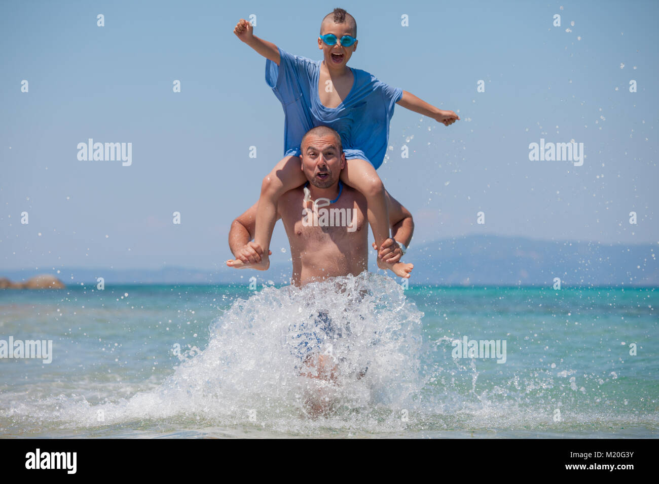 Gli spruzzi di figlio Padre spalle mare divertente Foto Stock