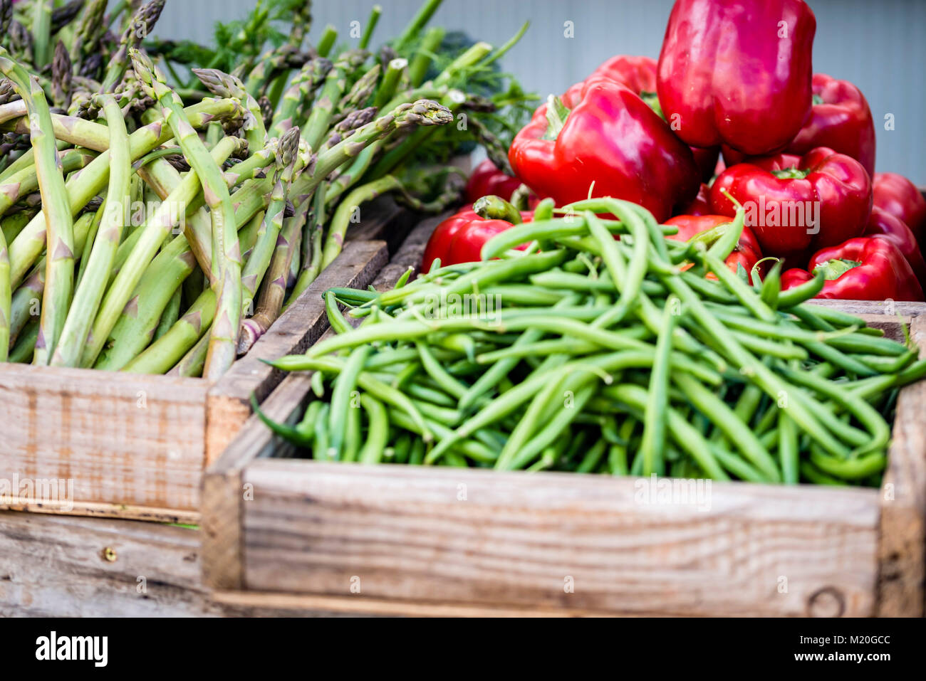 Organici di verdure fresche in scatole di legno visualizzati al mercato, closeup. Fagioli verdi, asparagi, rosso capsicum al mercato in stallo, Sydney, Australia. Foto Stock