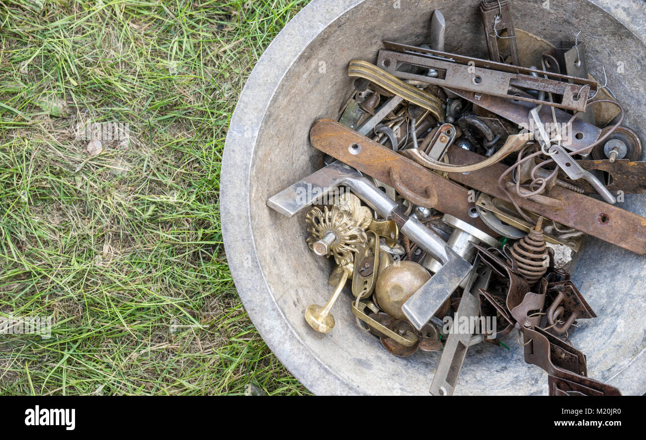 Recipiente di metallo con diversi accessori per porte su un mercato delle pulci Foto Stock