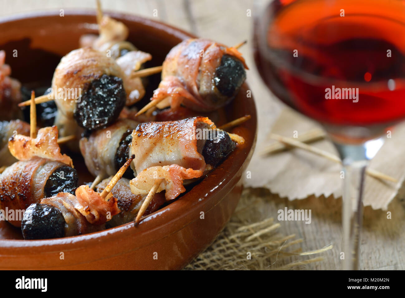 Deliziose tapas spagnole: fritto prugne avvolto in pancetta servita portoghese con il vino di porto Foto Stock