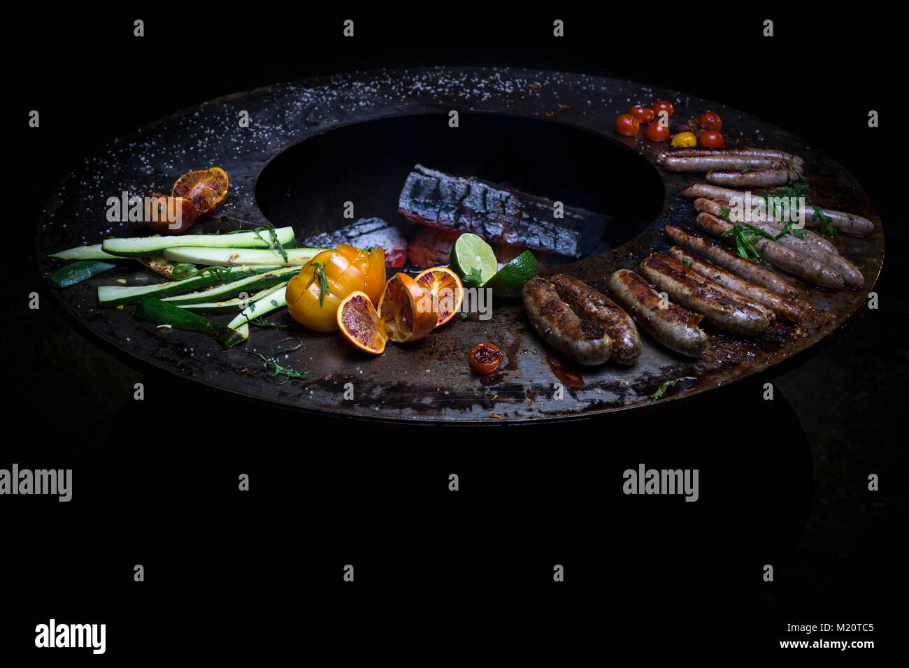 Salsiccia cottura su un braciere-grill. Questo nuovo concetto - tre in uno - combina i vantaggi della cottura con la plancha maggiorato di un barbecue e il braciere. Foto Stock