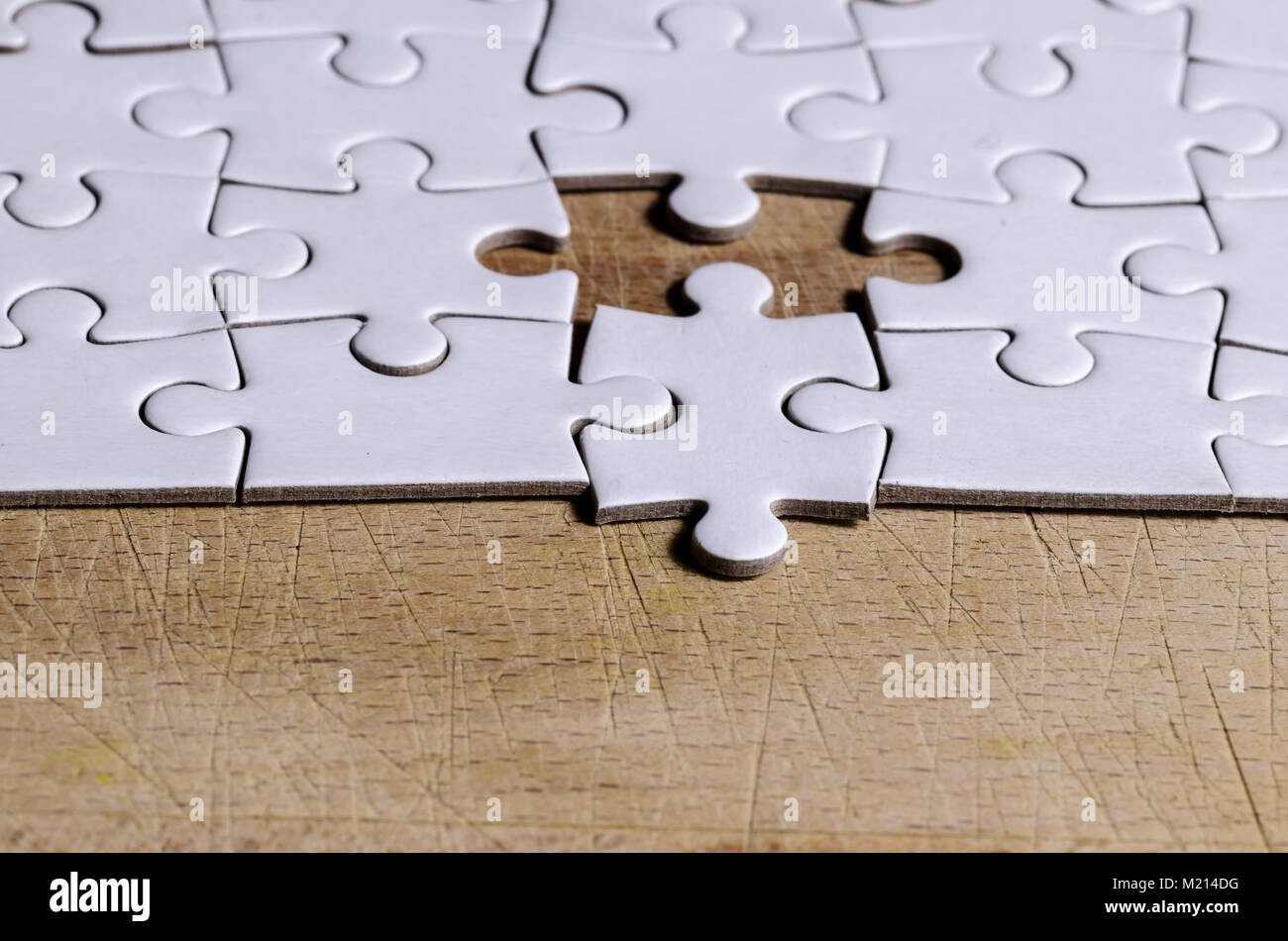 Bianco/jigsaw puzzle con un pezzo in posizione errata, su tavoli in legno nero sfondo, simbolo di problem solving e nuova visione Foto Stock
