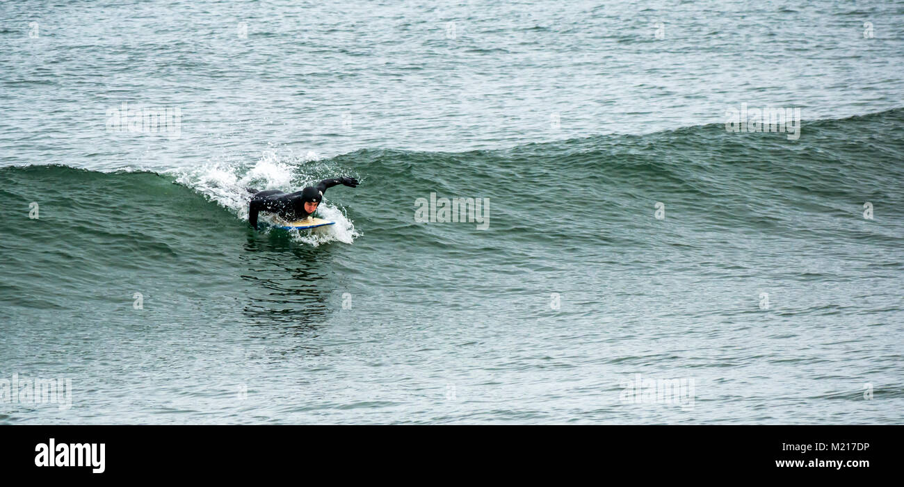 Sandend, Aberdeenshire, Scozia, Regno Unito. Un surfista fuori in inverno freddo onde del mare in una giornata grigia. Il picco del Mare del Nord crea buone condizioni di surf Foto Stock